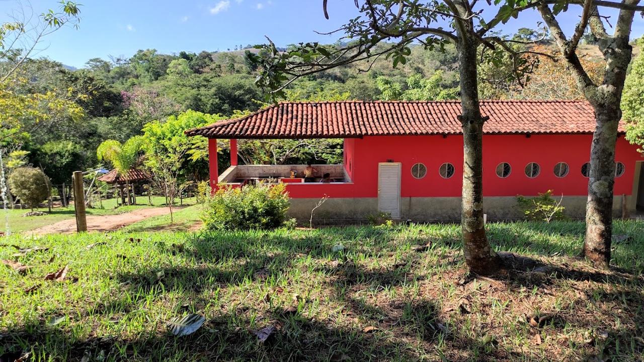 Área do Camping Ouro Fino com gramado e casa de alvenaria vermelha